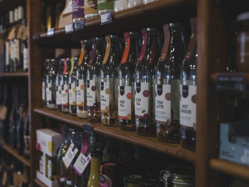 Free A variety of bottled beverages arranged on wooden shelves in a cozy shop setting. Stock Photo
