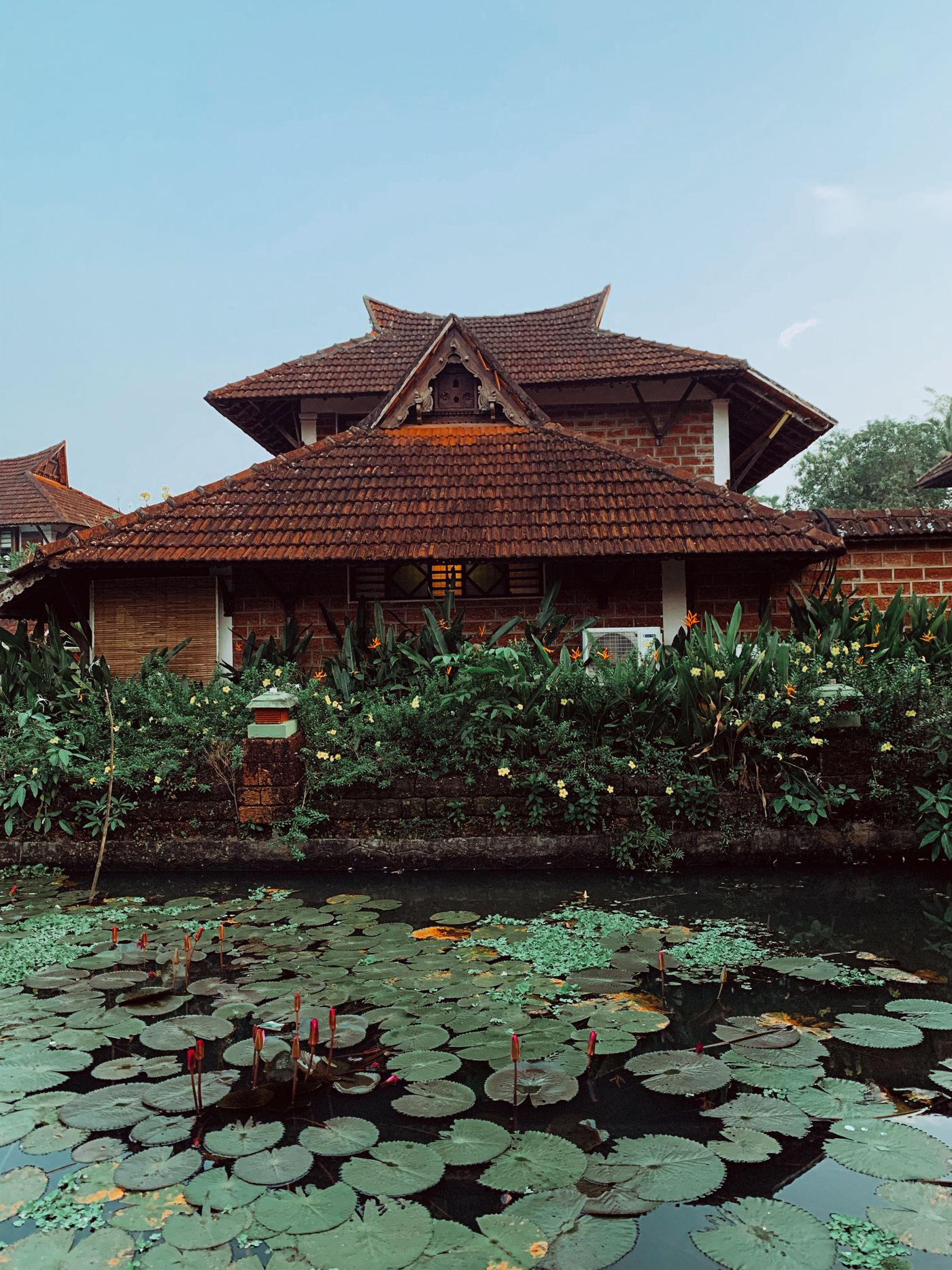 Tiled Kerala-style pavilion above a lily pond — representative image
