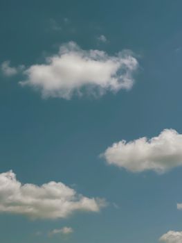 A peaceful sky with bright blue backdrop and fluffy white clouds floating gracefully.