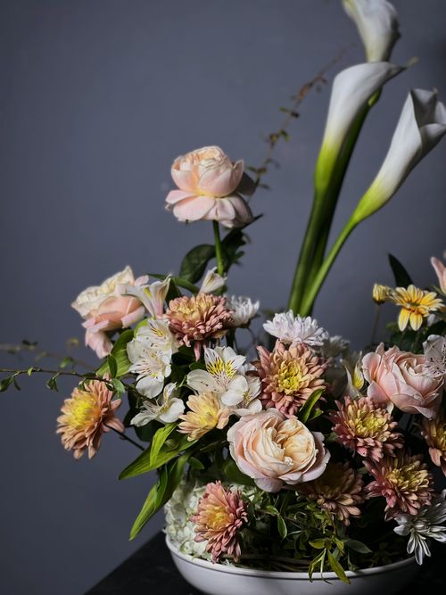 Free Floral arrangement featuring roses, lilies, and chrysanthemums on a dark background. Stock Photo