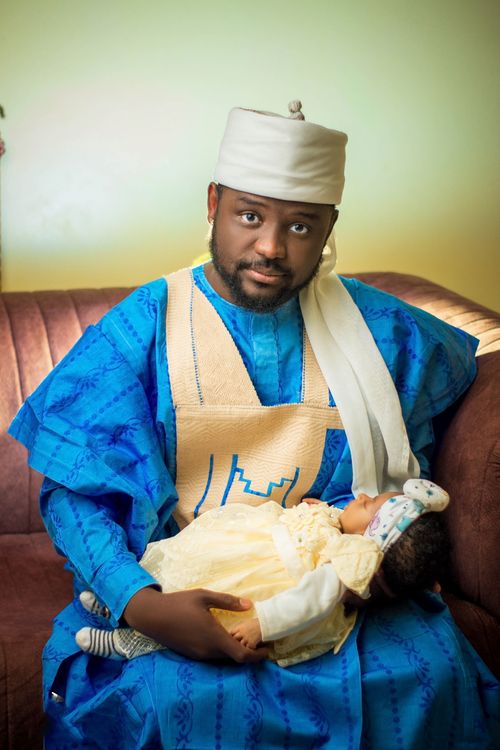 Free A father in traditional blue attire lovingly cradling a sleeping baby in a cozy setting. Stock Photo