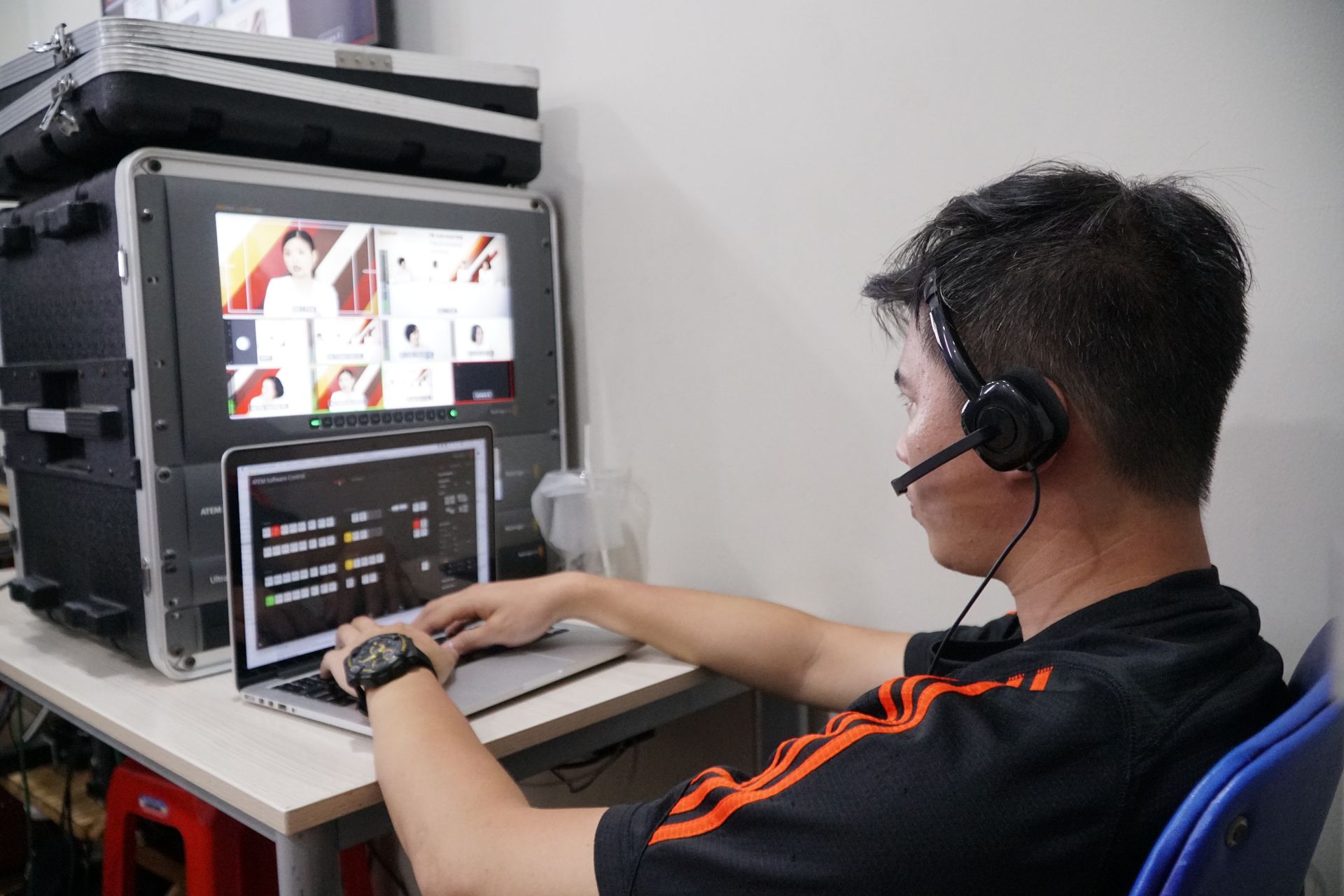 Technician manages multiple video feeds using laptop and monitor in studio setting.