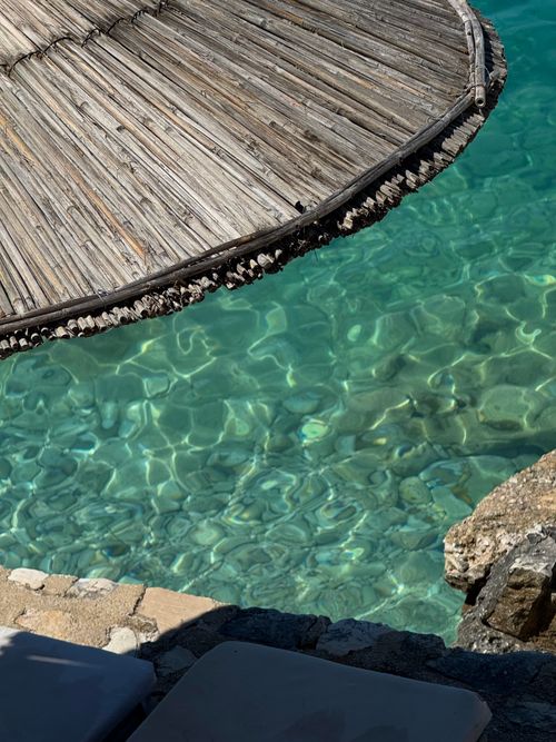 Free Relaxing beach setting with clear water and straw umbrella, perfect for a serene getaway. Stock Photo
