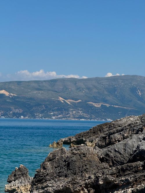 Free A breathtaking view of rugged coastal cliffs meeting the vibrant blue sea under a clear summer sky. Stock Photo