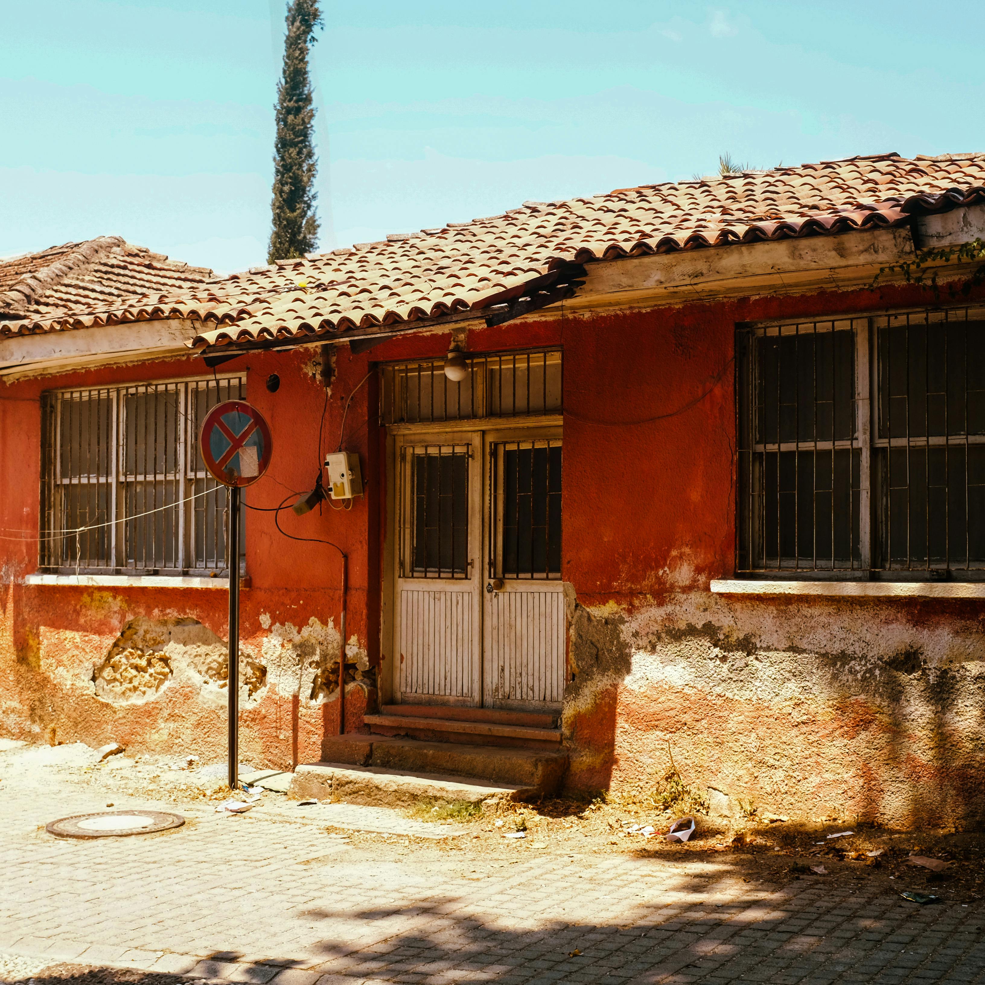 A charming rustic house with weathered red walls under a bright sunny sky, exuding vintage vibes.