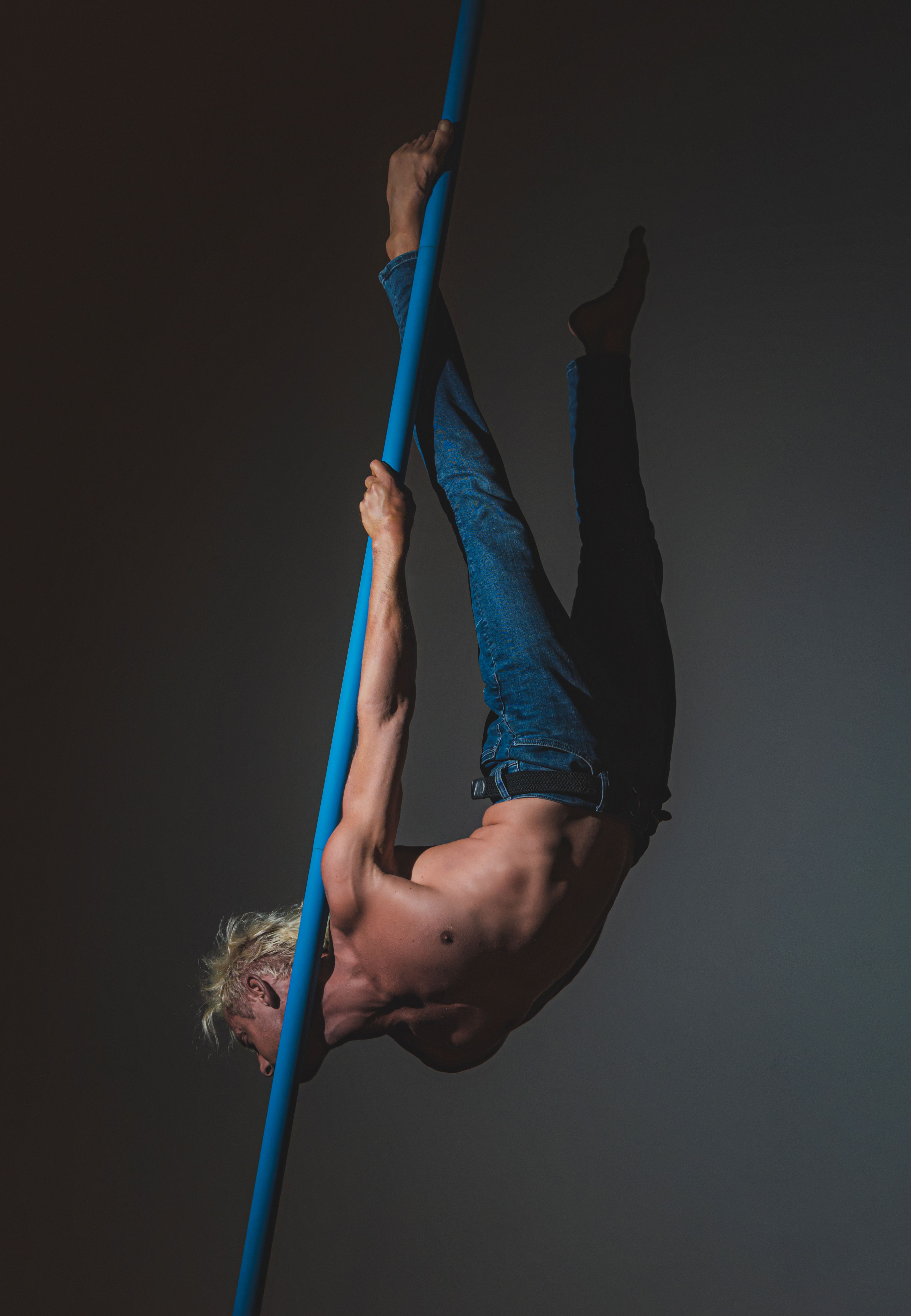 Male acrobat performs an impressive pole routine, showcasing strength and flexibility.