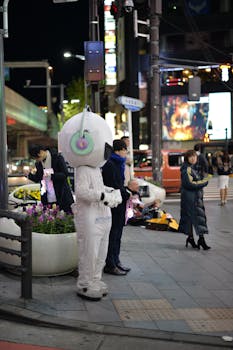 A vibrant night scene at a Tokyo intersection featuring people and a unique mascot character.