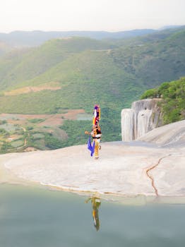 Traditional dancer performs at Hierve el Agua, Oaxaca, with stunning natural backdrop.