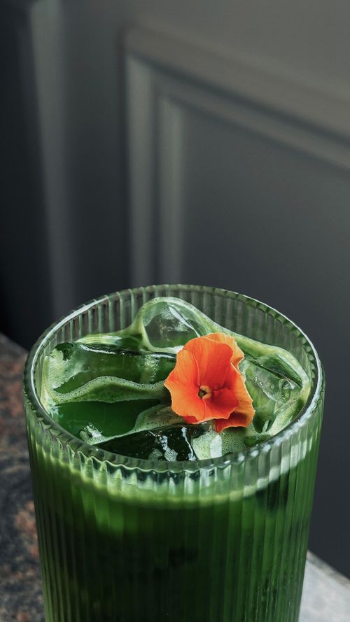 Free Close-up of a refreshing iced matcha tea garnished with an edible flower, highlighting vibrant colors. Stock Photo