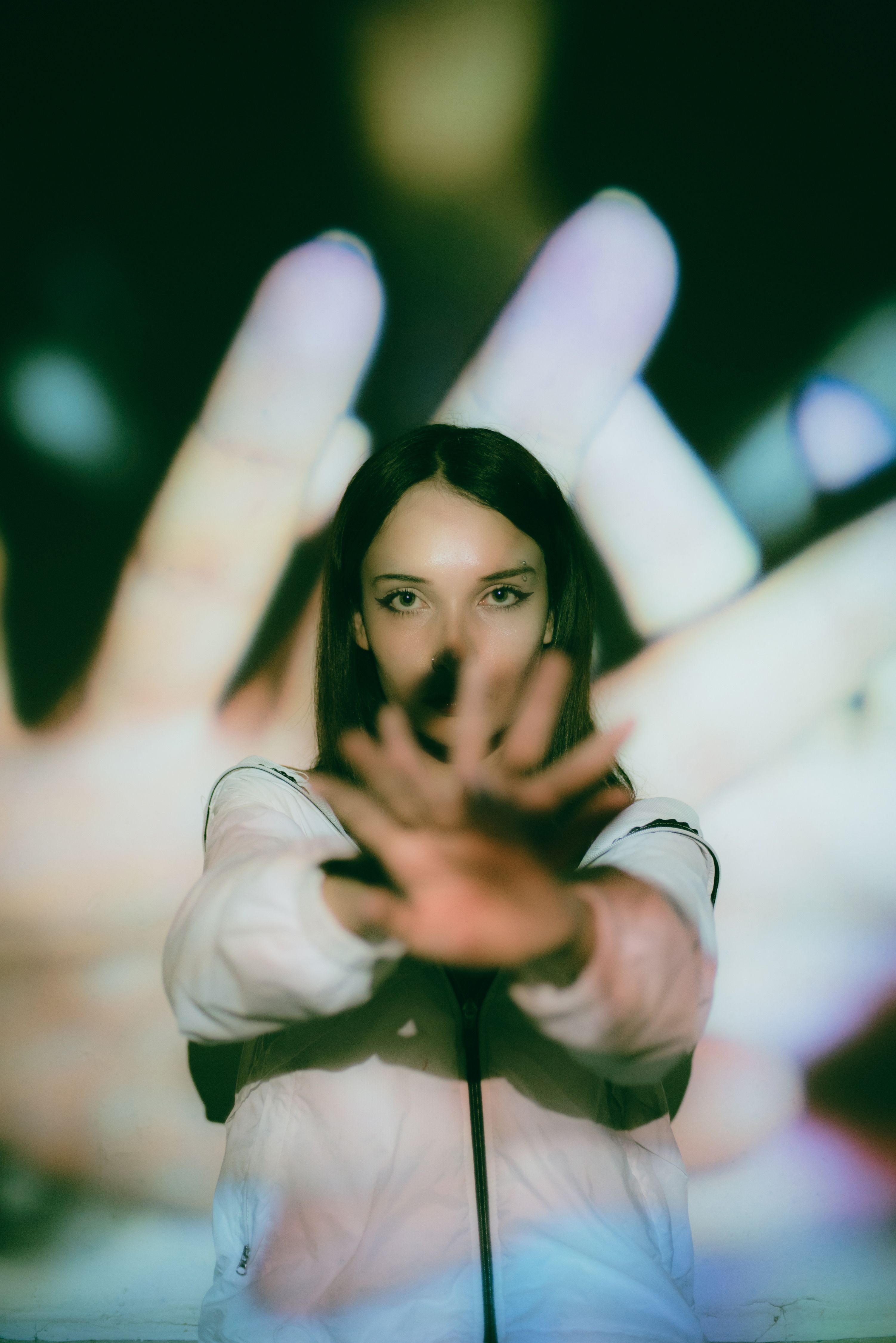 Artistic portrait of a woman with hands in focus and background projections, creating a conceptual visual.