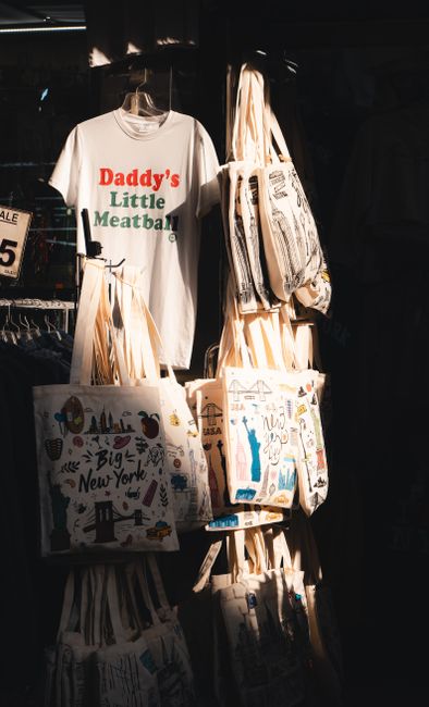 Souvenir shop display featuring tote bags and a humorous t-shirt in New York City. - Understanding Different Handbag Styles