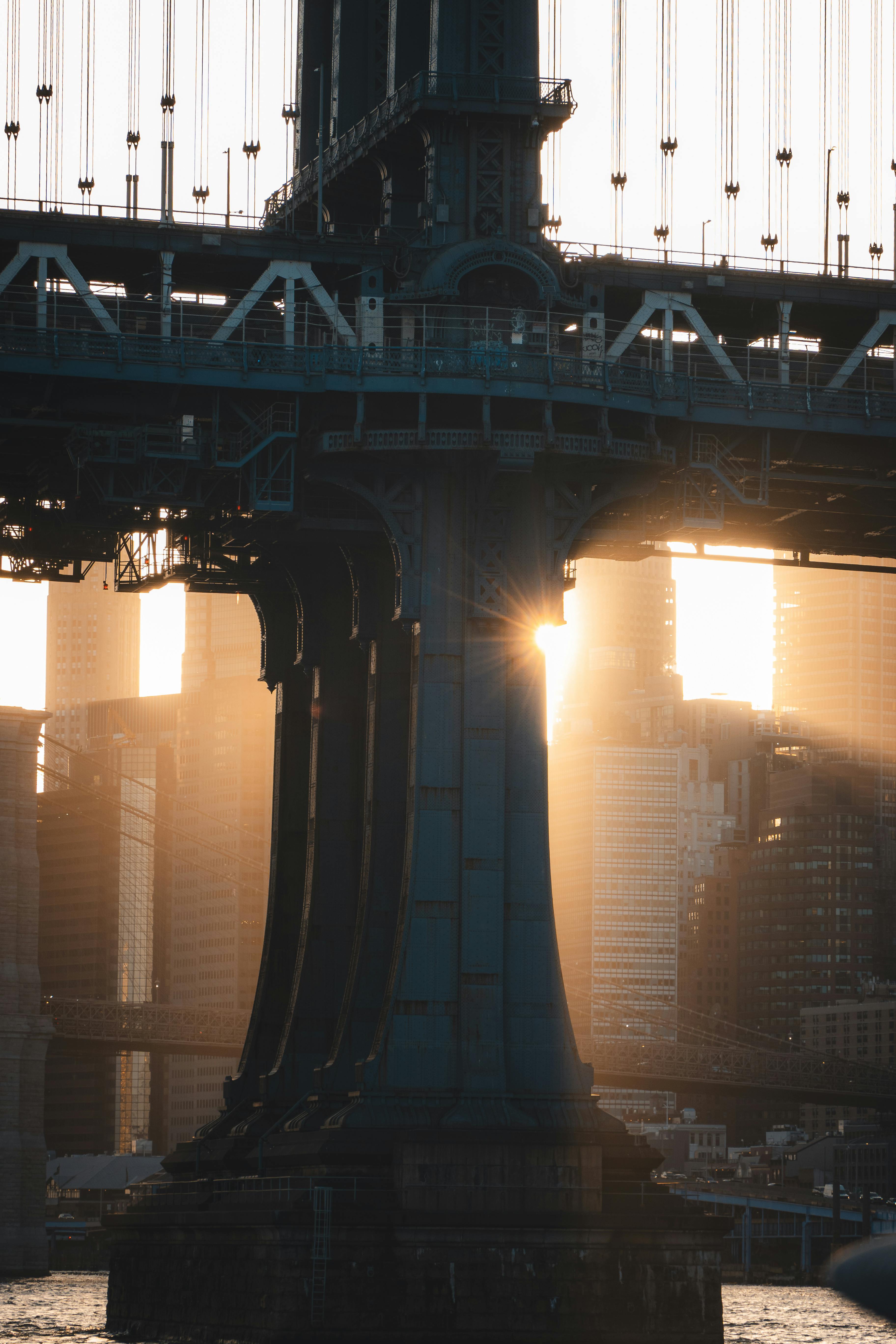 Dramatic sunset through the Manhattan Bridge with city skyline backdrop in New York City.