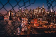 迷人的纽约市天际线在晚上通过篱笆和照明的摩天大楼展现