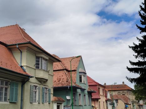 Colorful historical houses under a cloudy sky in Brașov, Romania.