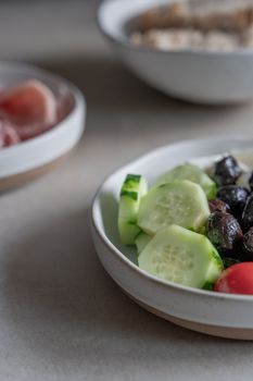 Close-up view of a fresh Mediterranean salad with sliced cucumbers, olives, and tomatoes.