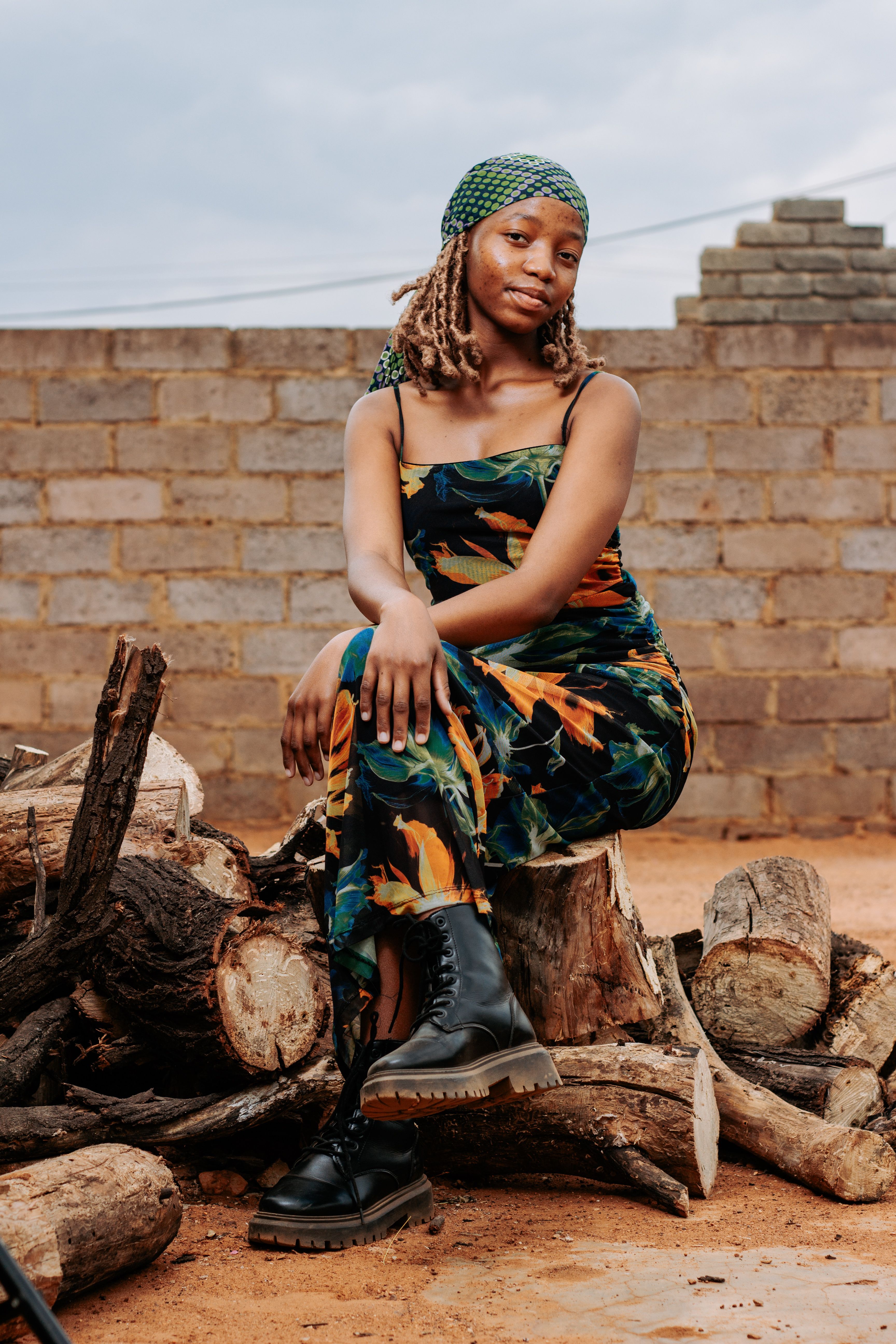 Portrait of Woman Sitting on Firewood Outdoors · Free Stock Photo