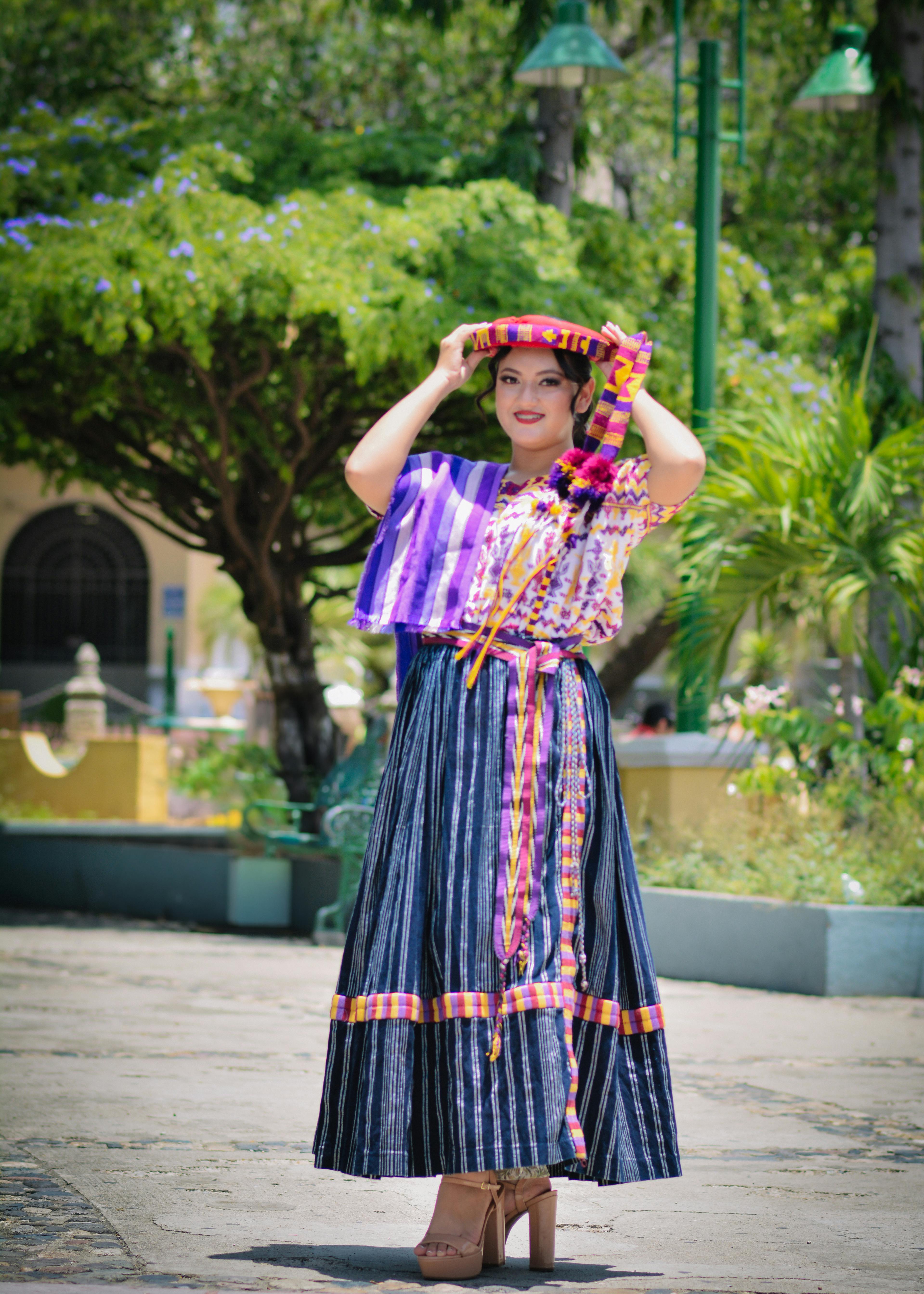 Woman in traditional attire posing outdoors with vibrant textiles.