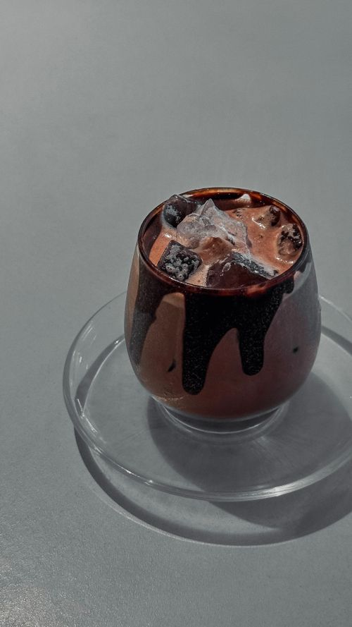 Free Close-up of a chilled chocolate drink with ice in a glass, perfect for a hot day outdoors. Stock Photo