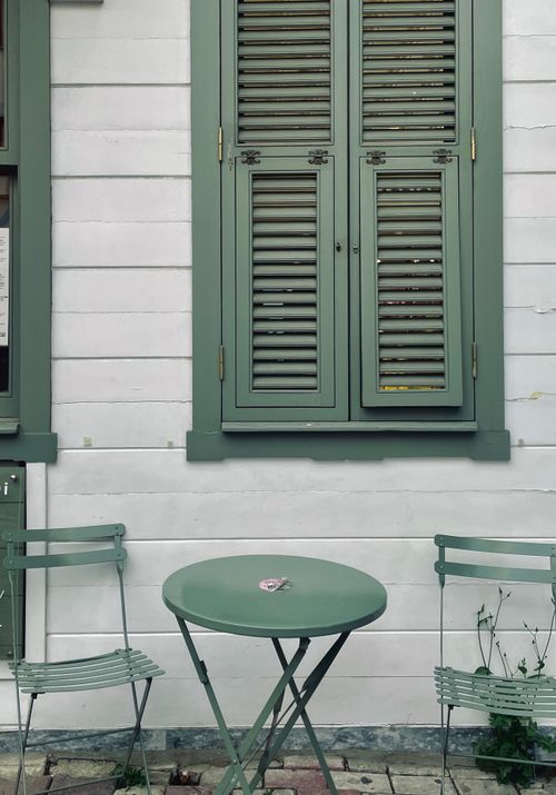Free A quaint outdoor café with green furniture against a white wooden wall in İstanbul, Türkiye. Stock Photo