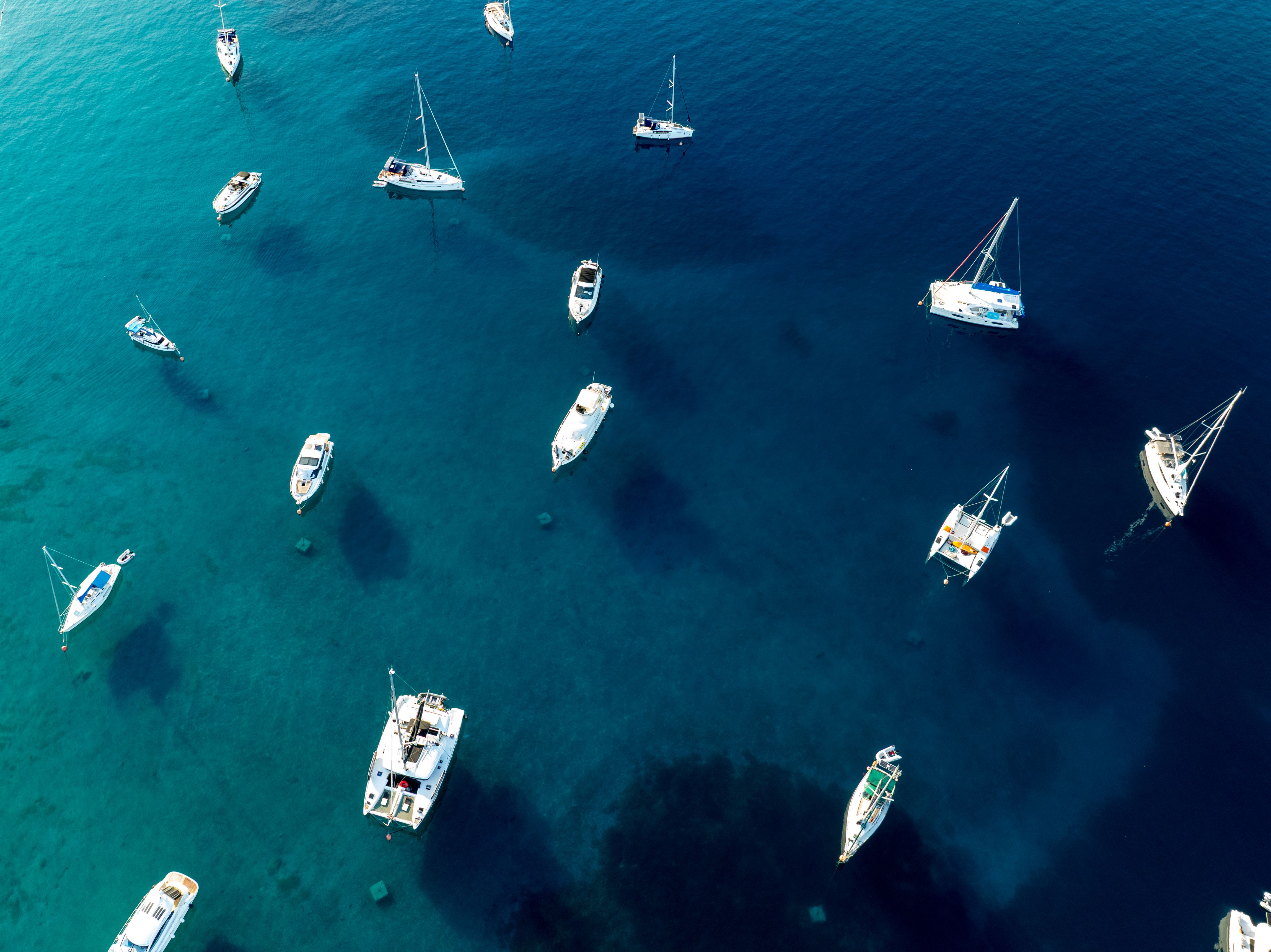 Aerial view of boats anchored in clear blue waters near Primošten, Croatia, showcasing a serene maritime setting.