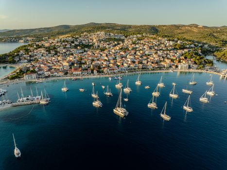 A stunning aerial view of Primošten's harbor featuring numerous sailboats under a clear summer sky.