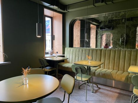 Chic cafe interior in Warsaw featuring green velvet seating and minimalist decor.