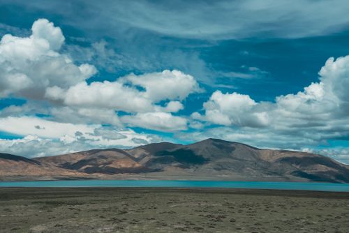 Free Vast scenic landscape featuring mountains, a lake, and a dramatic cloudy sky. Stock Photo