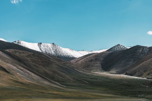 Scenic view of snow-covered mountain peaks with a clear blue sky, ideal for nature enthusiasts.