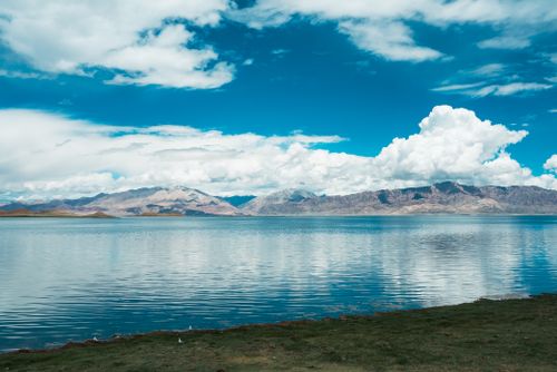 Free Stunning landscape of a serene lake with mountains and blue skies, perfect for travel themes. Stock Photo