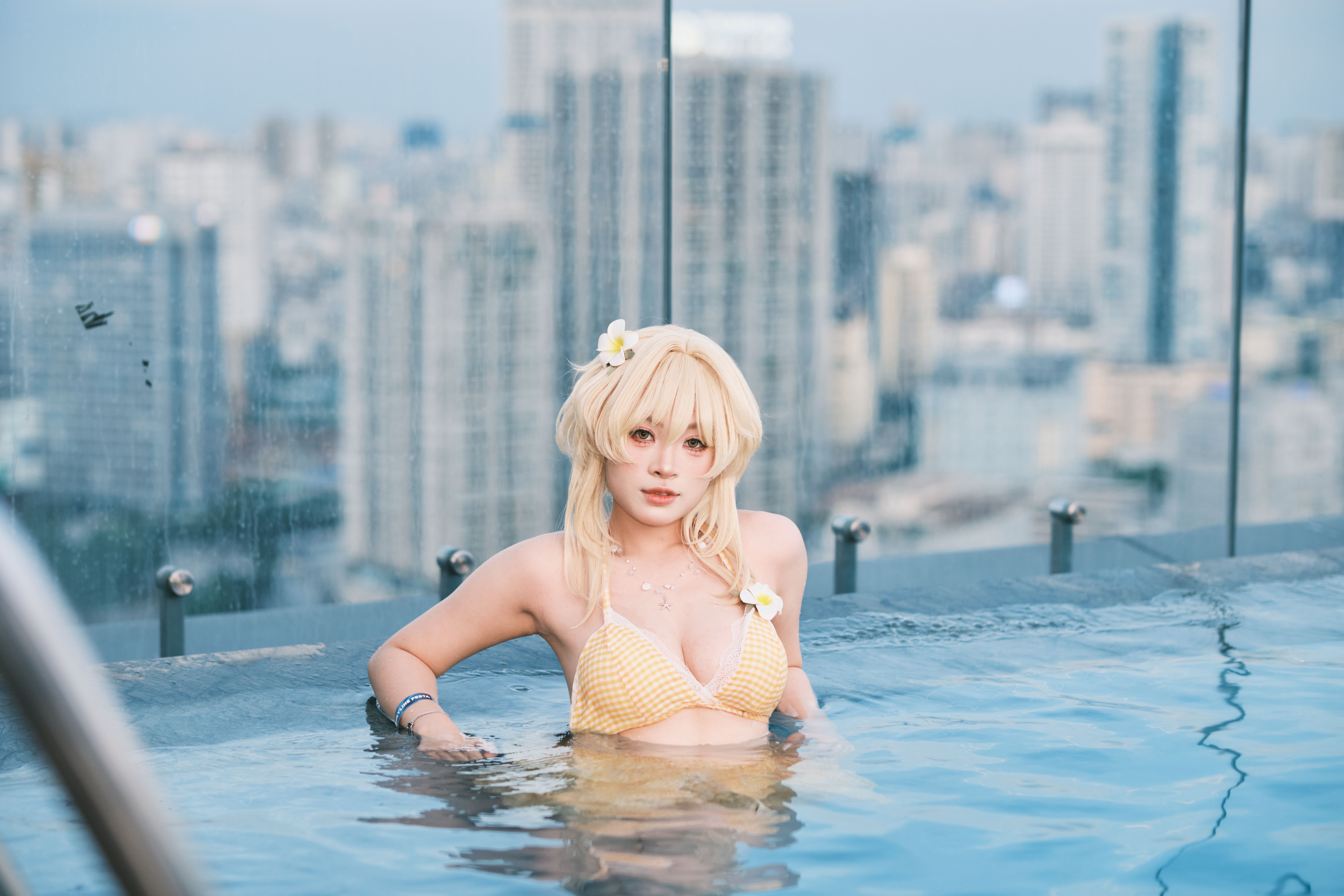Woman relaxing at a rooftop pool with a vibrant city skyline backdrop.