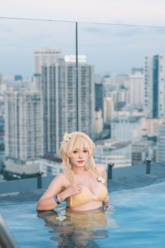 A young woman in a bikini cosplays in a rooftop pool, overlooking a cityscape.