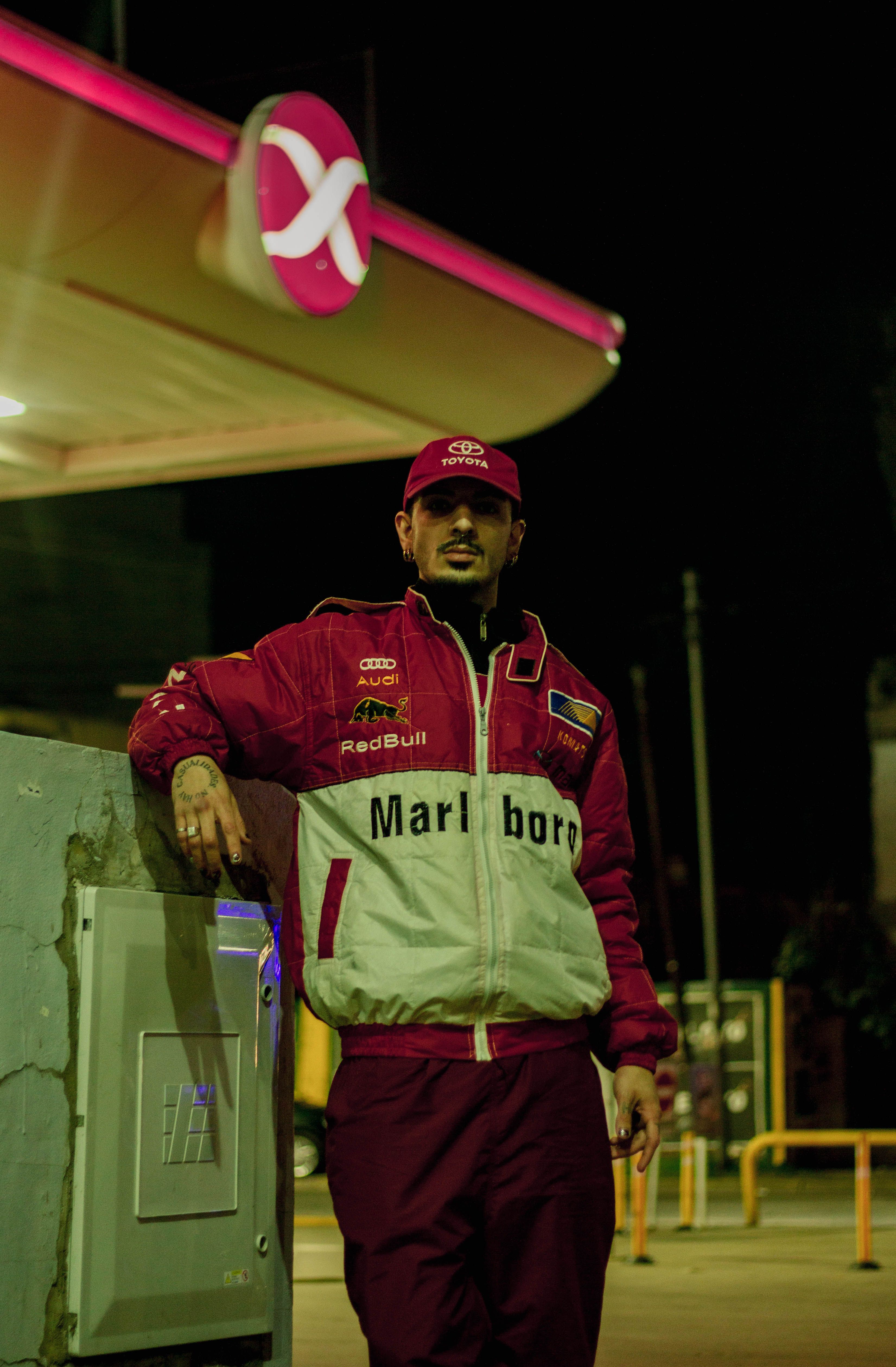 Man in racing gear at a gas station in Argentina, night scene.