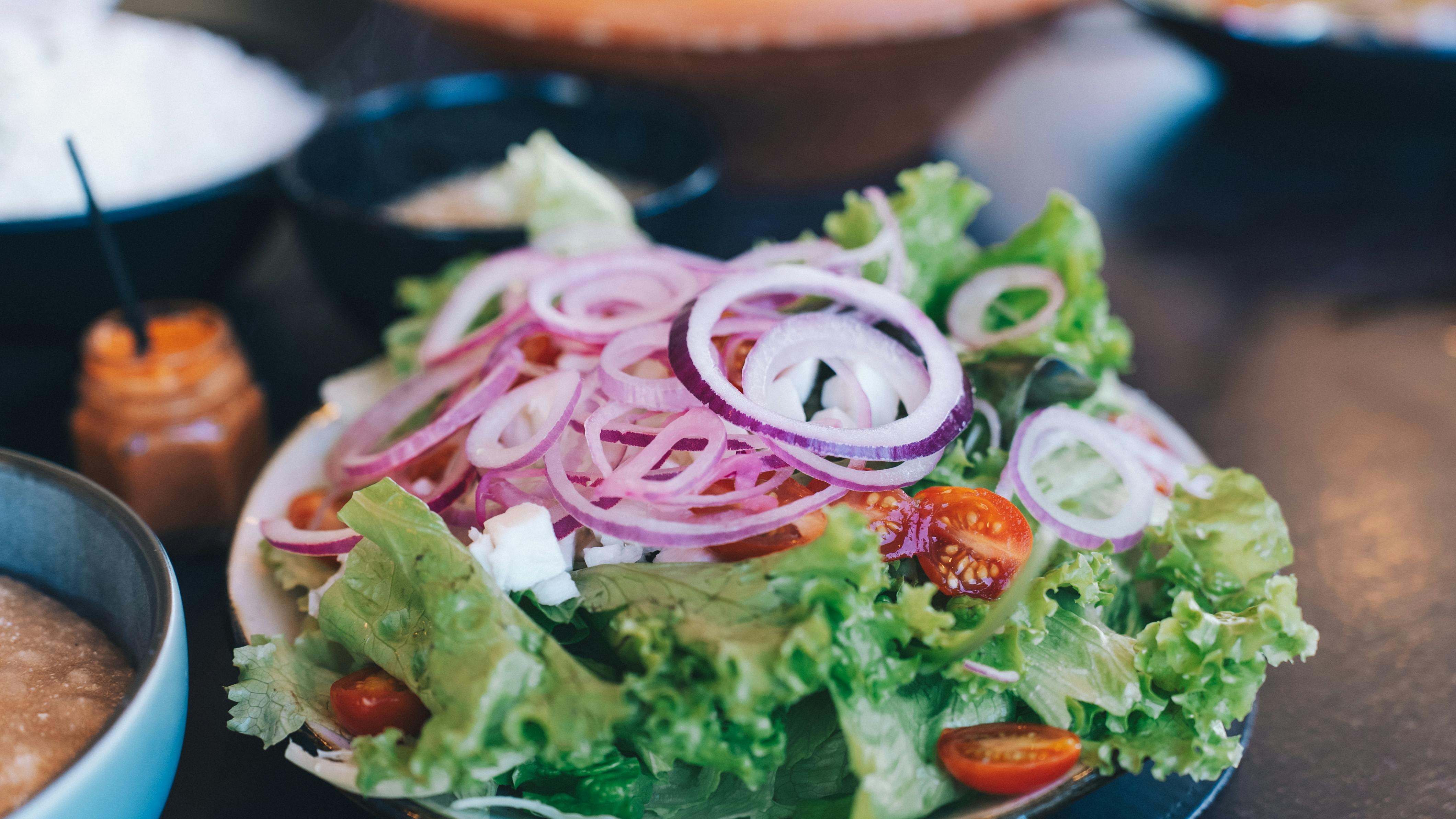 Colorful salad with lettuce, onions, tomatoes, and feta cheese, perfect for a healthy meal.