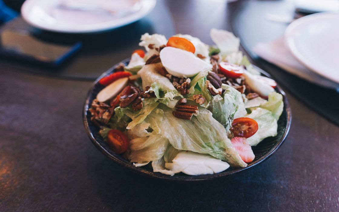 Delicious fresh salad with cherry tomatoes, nuts, and mozzarella in a bowl.