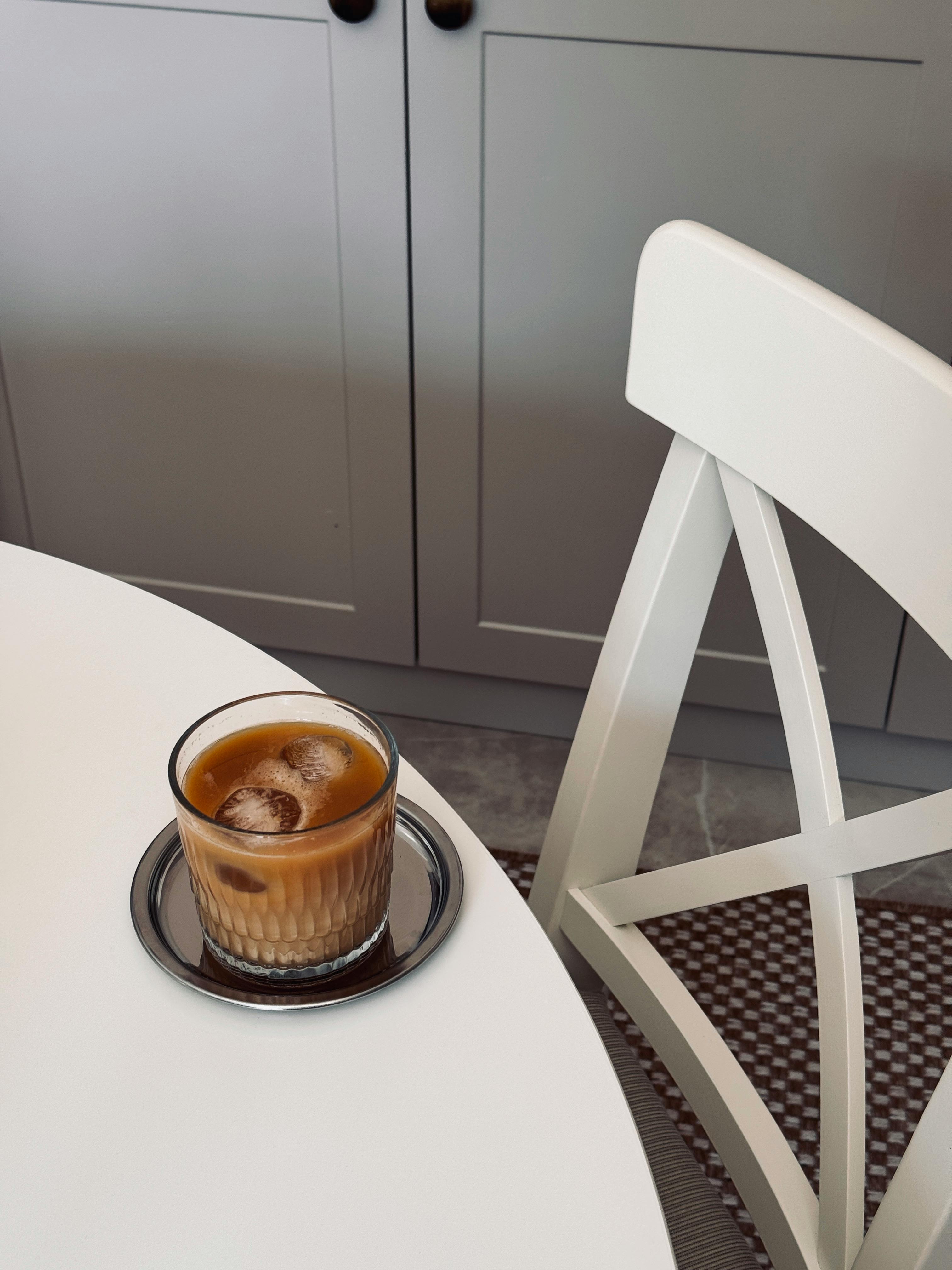 Iced coffee on a white table in a cozy kitchen setting, inviting and modern.