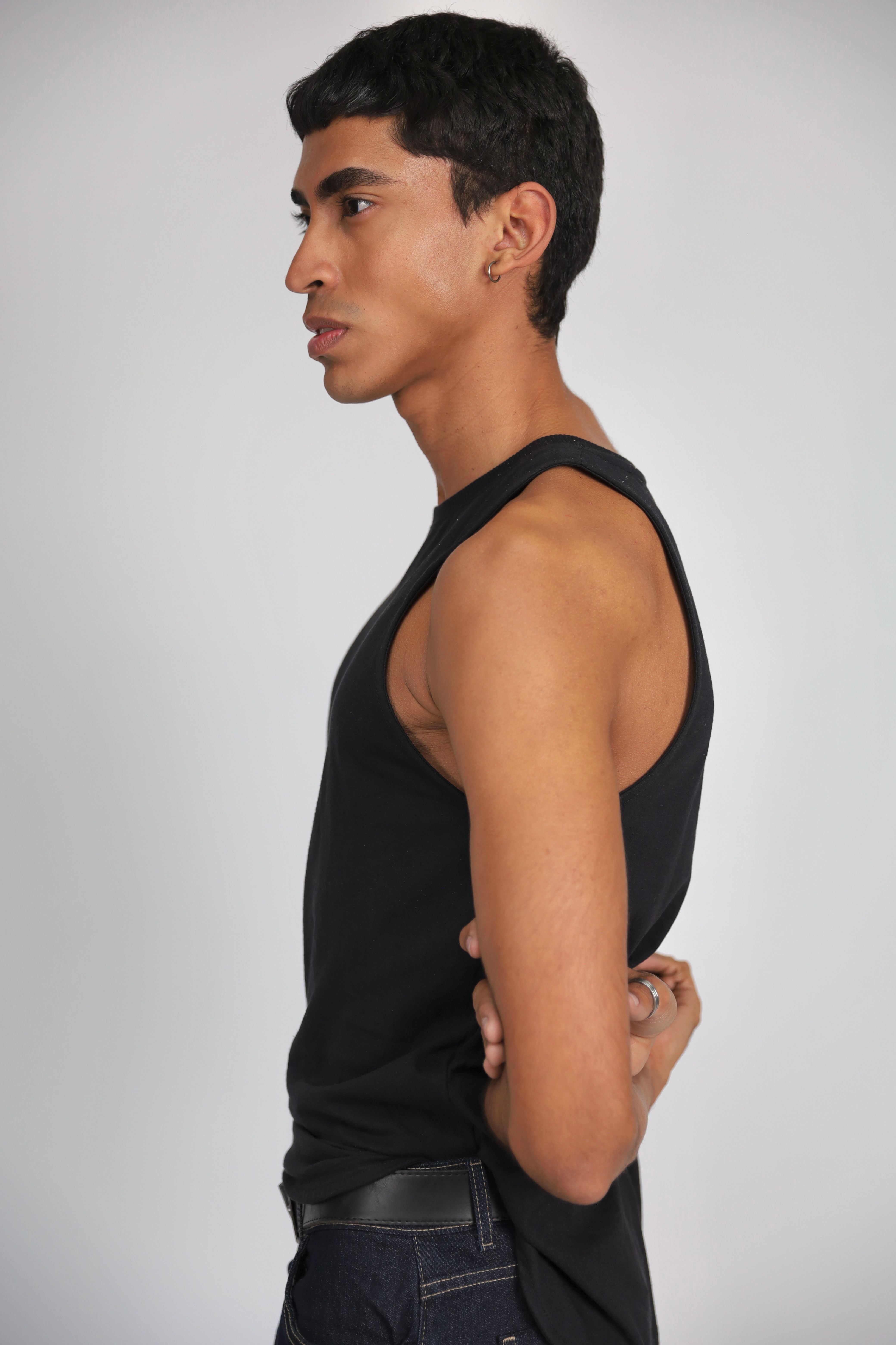 Side profile of a young adult wearing a black tank top, showcasing modern style and fashion.