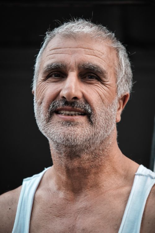 Free Close-up portrait of a smiling senior adult man with a beard, captured outdoors, showcasing warmth and friendliness. Stock Photo