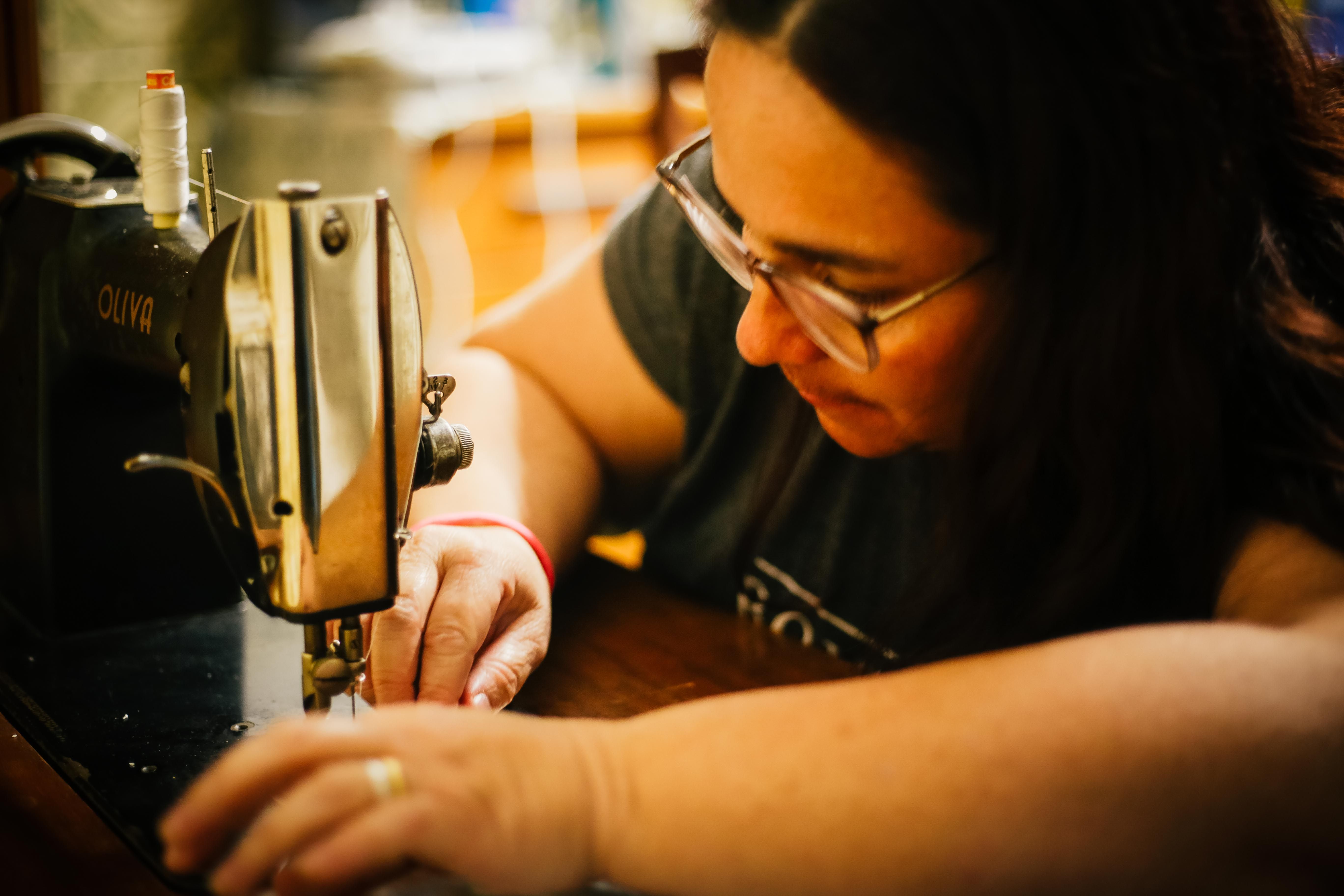 A skilled seamstress concentrates deeply while using a vintage sewing machine in a cozy indoor setting. — Maynard Longarm Quilting