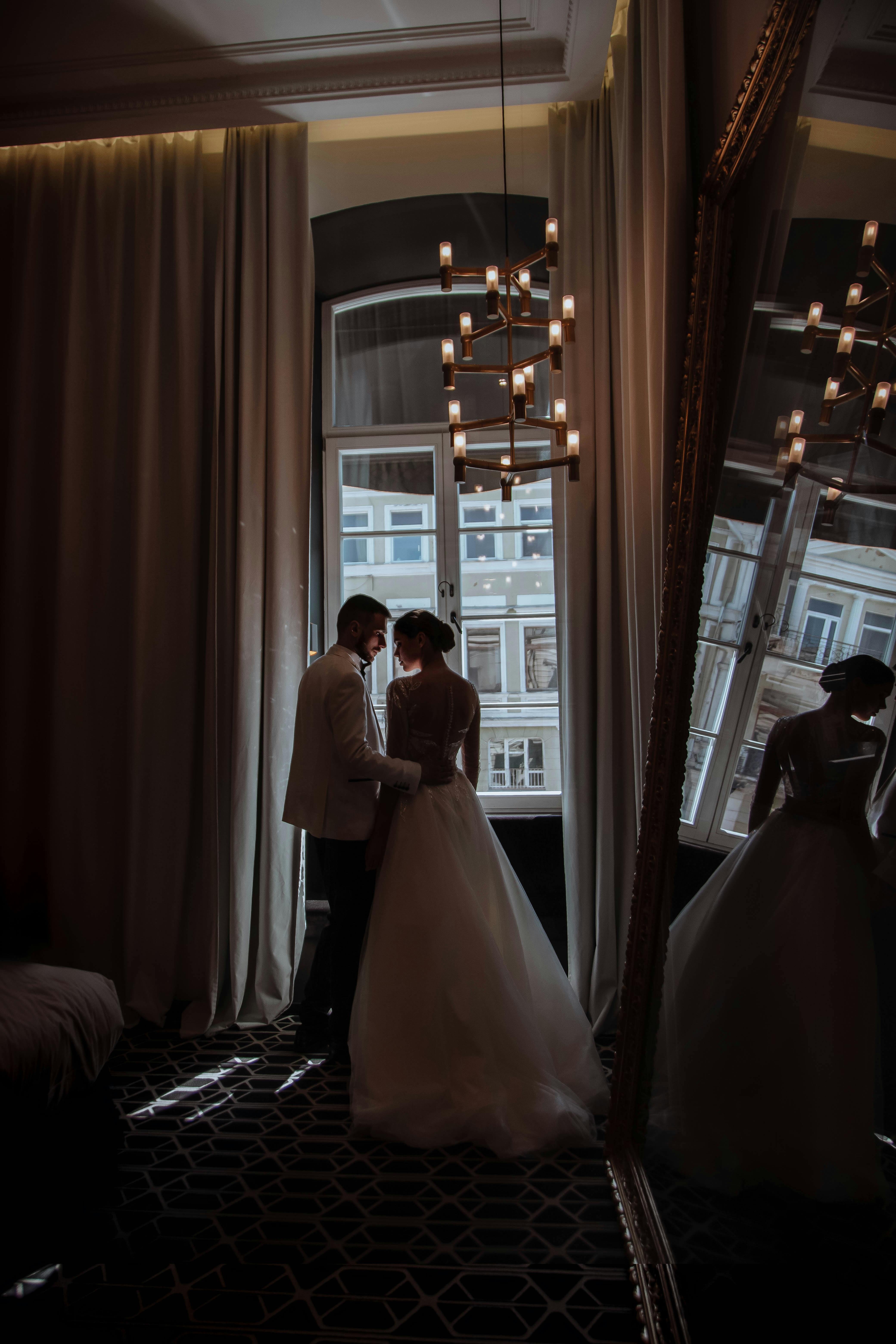 Bride and groom sharing a moment in soft indoor lighting with elegant reflections.