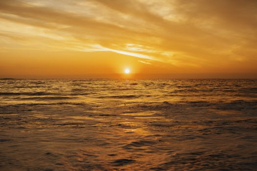 A breathtaking gold-hued sunset over the ocean in Cape Town, South Africa, captured in serene beauty.