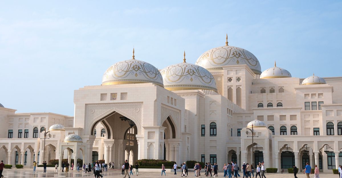 Majestic view of Qasr Al Watan Palace with visitors in Abu Dhabi under clear skies.