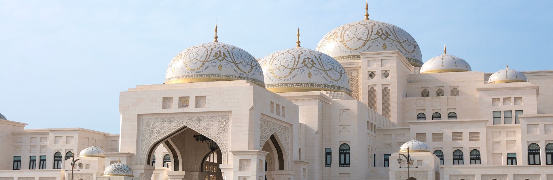 Majestic view of Qasr Al Watan Palace with visitors in Abu Dhabi under clear skies.