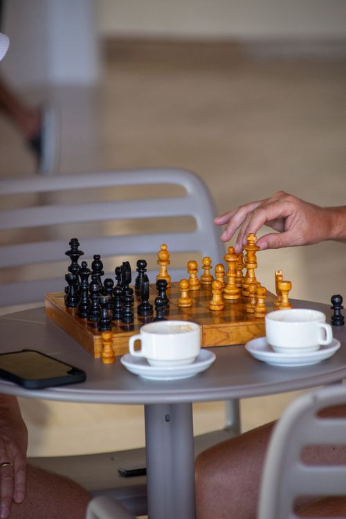 Free A close-up of a chess game with coffee cups on a table in a relaxed setting. Stock Photo
