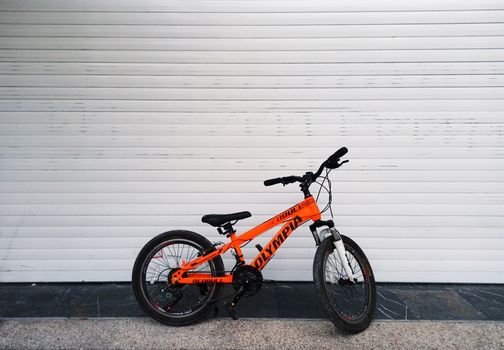 Vibrant orange bicycle resting on a seamless white backdrop, showcasing minimalist design.