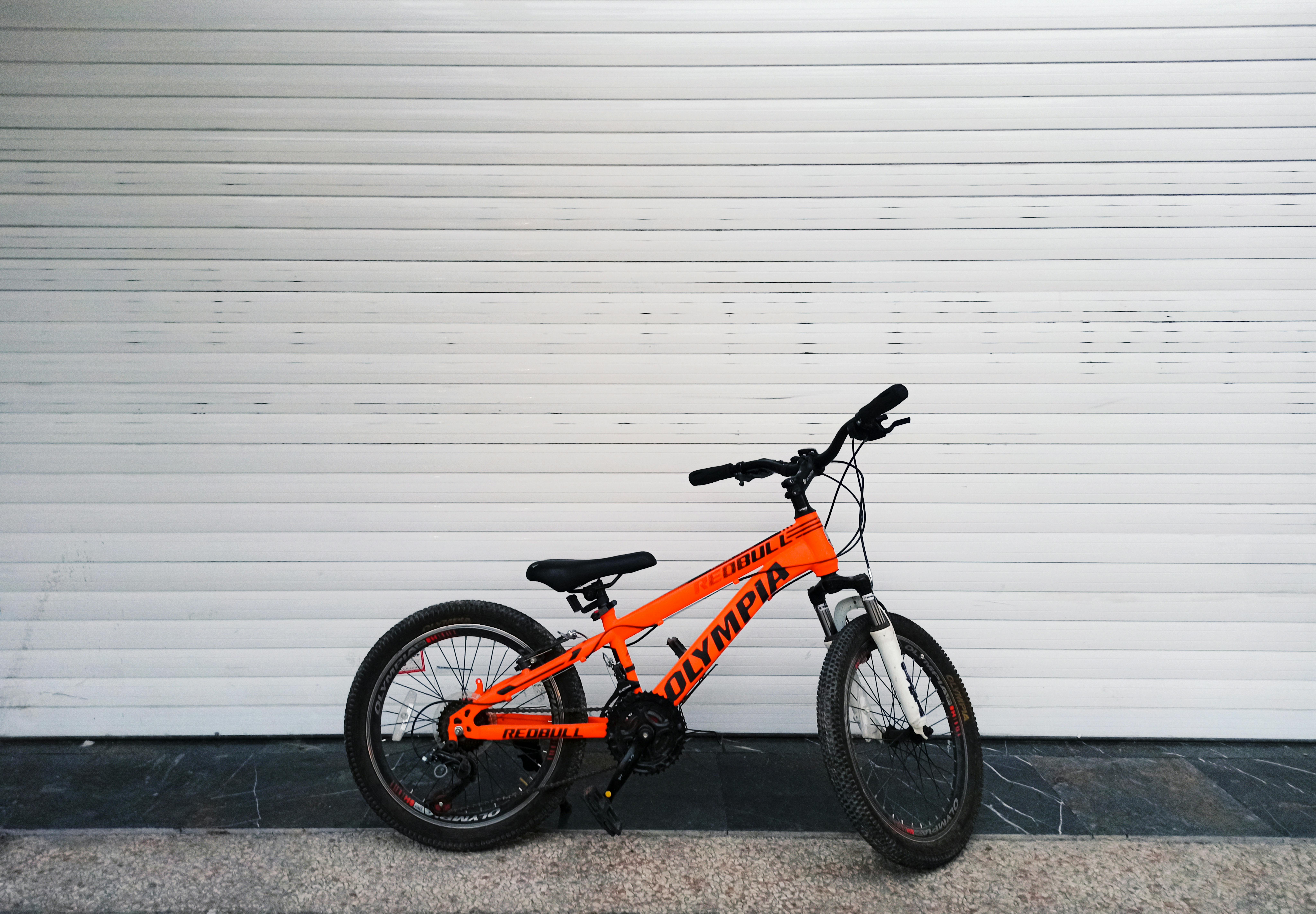 Free Vibrant orange bicycle resting on a seamless white backdrop, showcasing minimalist design. Stock Photo