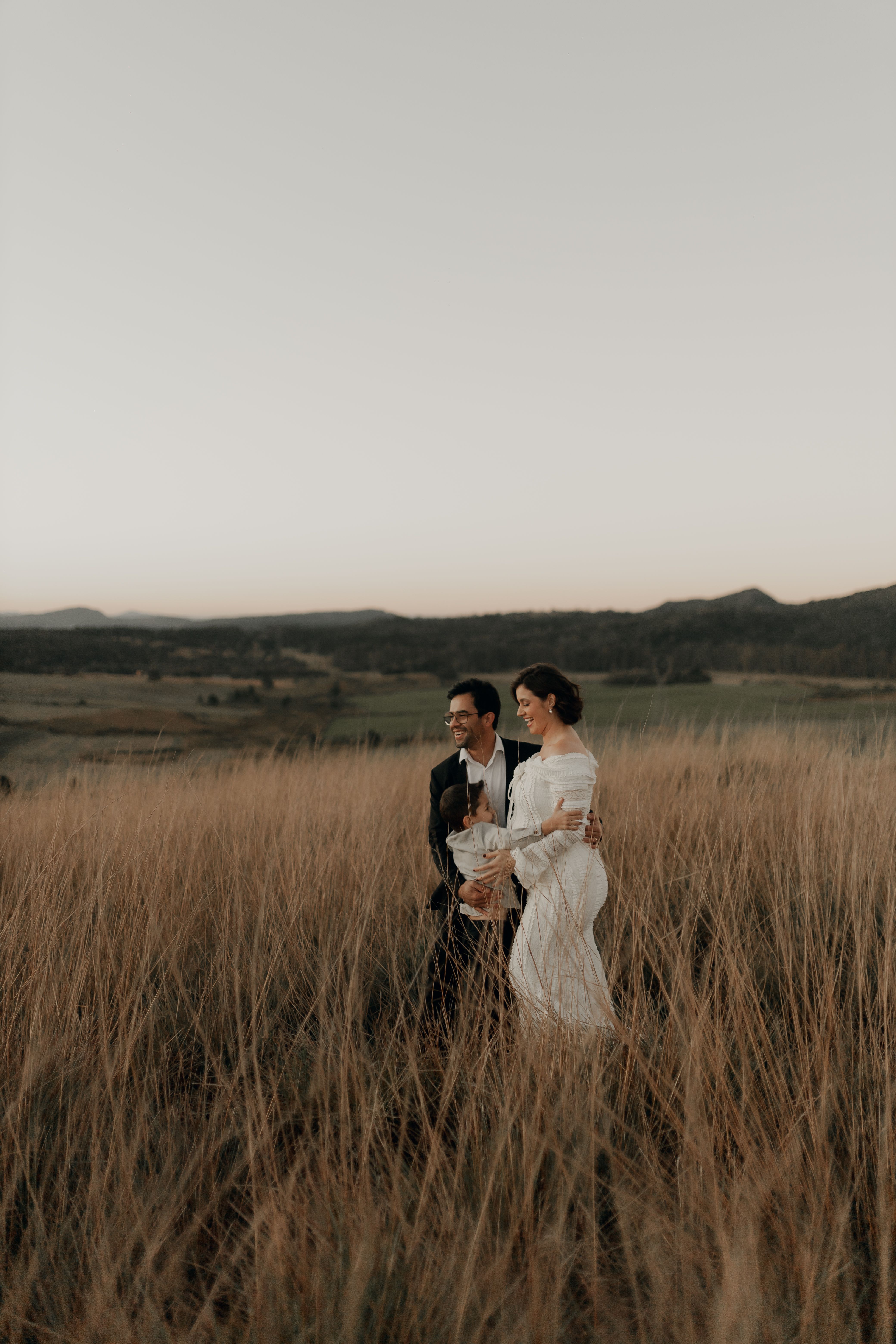 A loving couple strolls through a scenic field at sunset, embracing nature.
