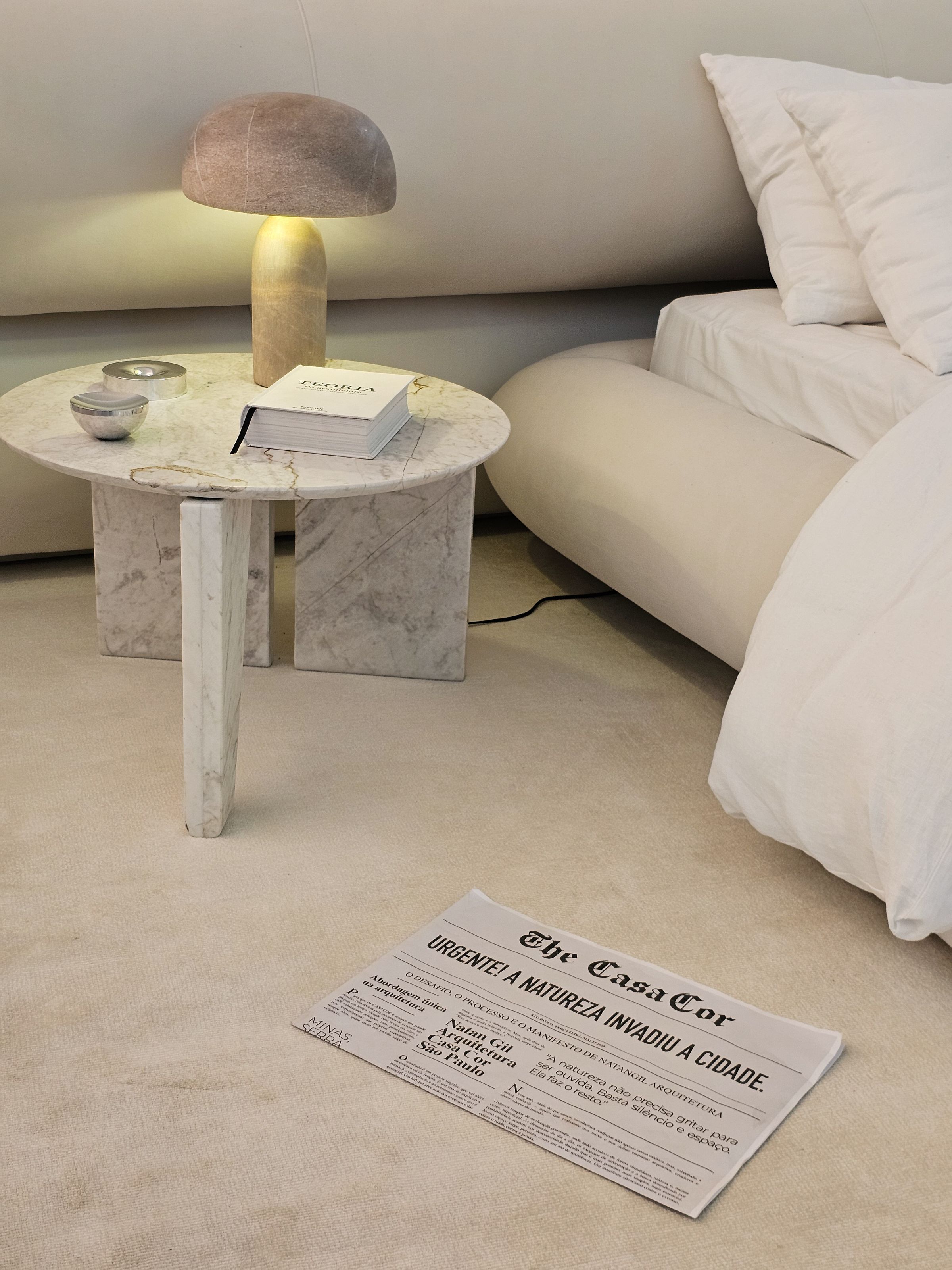 Bedroom corner with a marble bedside table, lamp, books and upholstered headboard