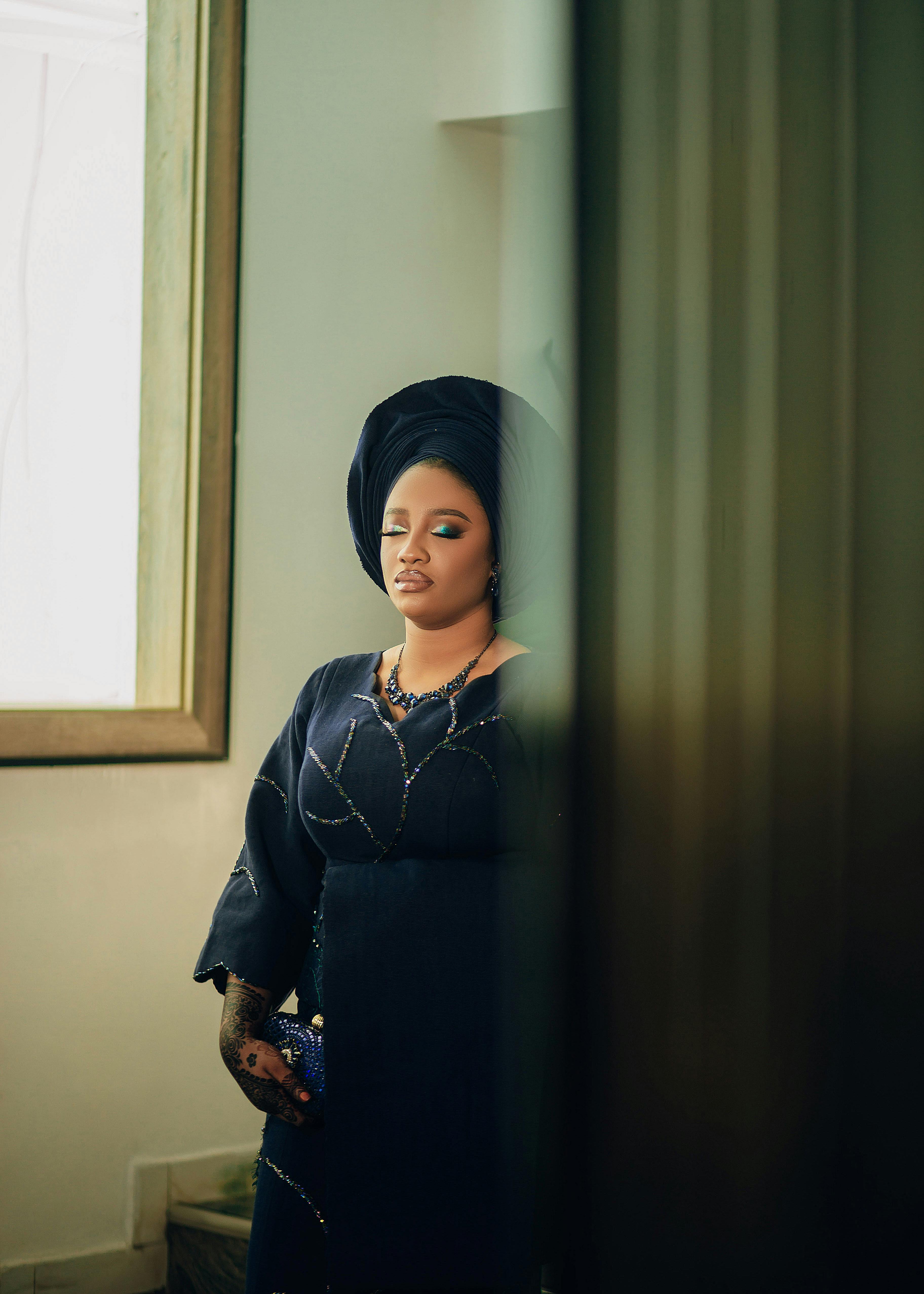 Free A stylish woman in elegant African attire standing indoors with a reflective mood. Stock Photo