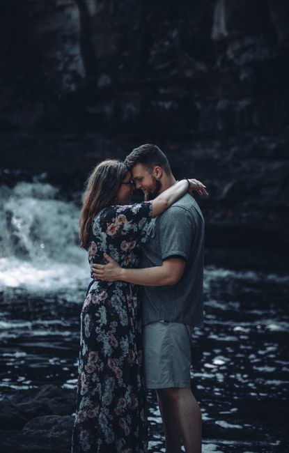 Couple embracing by a waterfall in a serene outdoor setting, exuding love and intimacy.