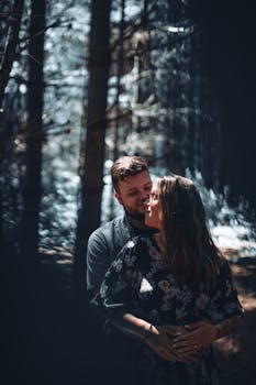 A loving couple sharing an intimate moment in a sunlit, serene forest setting.